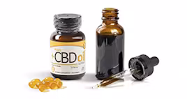 CBD oil bottle, dropper, and softgel capsules on a white background